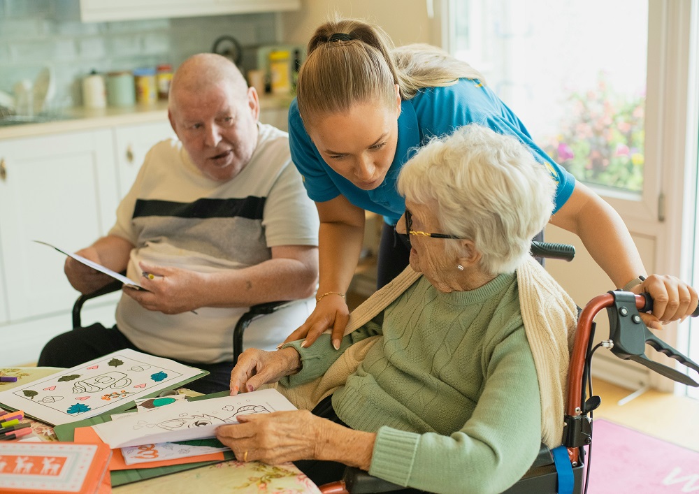 A carer helping two residents with an activity in a care home