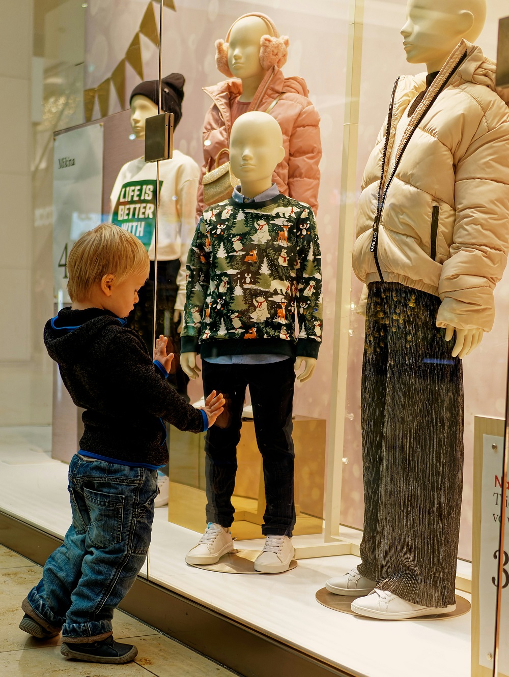A young child at a shop window in a shopping centre